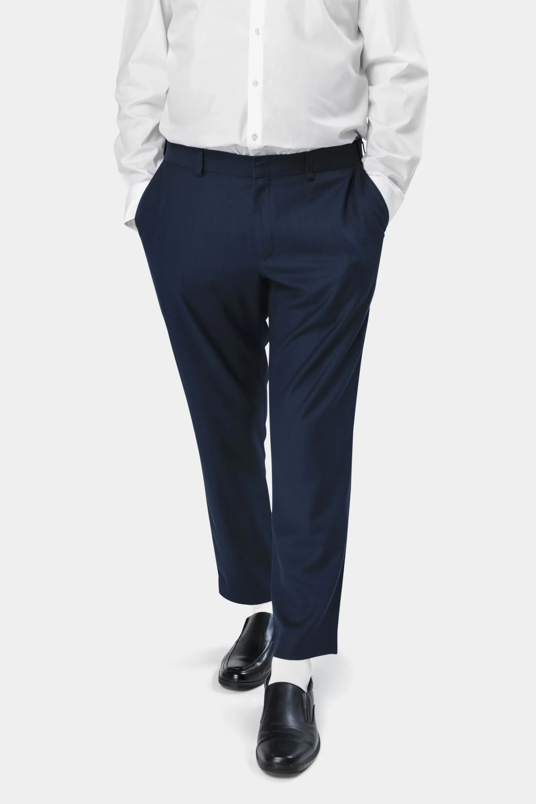 Homme portant un pantalon bleu marine élégant avec une chemise blanche et des mocassins noirs.